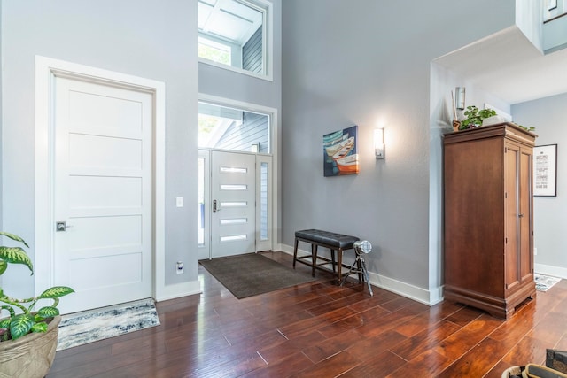 entryway with a towering ceiling and dark hardwood / wood-style flooring