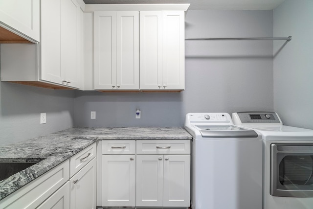 clothes washing area with cabinets, washer and dryer, and a textured ceiling