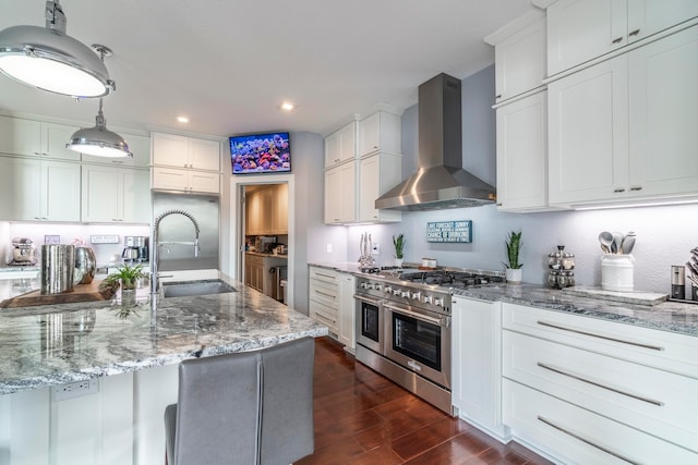 kitchen with wall chimney exhaust hood, range with two ovens, dark hardwood / wood-style flooring, and white cabinetry