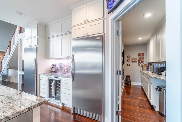 kitchen featuring beverage cooler, stainless steel fridge, dark wood-type flooring, and white cabinetry