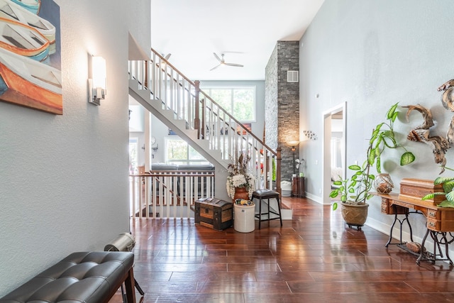 stairway with a towering ceiling, hardwood / wood-style flooring, and ceiling fan