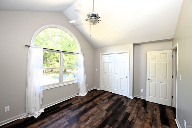 unfurnished bedroom with lofted ceiling, ceiling fan, dark wood-type flooring, and a closet