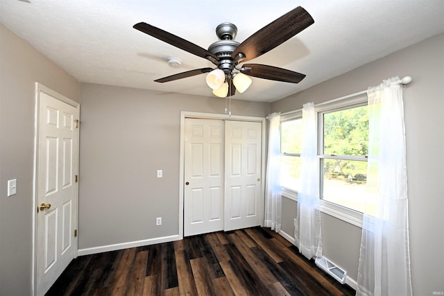 unfurnished bedroom featuring dark wood-type flooring, a closet, a textured ceiling, and ceiling fan