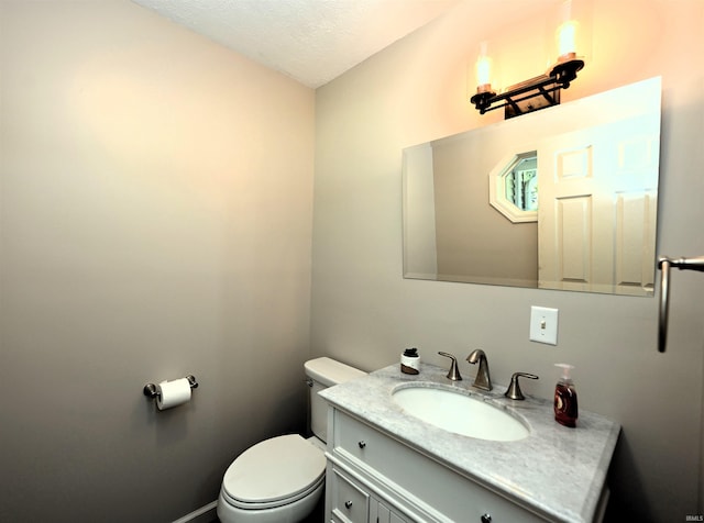 bathroom with a textured ceiling, vanity, and toilet