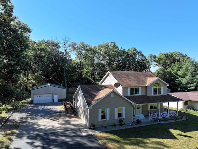 view of front facade with an outbuilding, covered porch, a front yard, and a garage