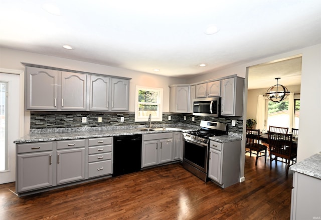 kitchen with light stone counters, decorative backsplash, stainless steel appliances, dark wood-type flooring, and gray cabinets