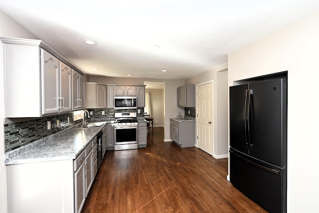 kitchen with dark hardwood / wood-style floors, stainless steel appliances, tasteful backsplash, gray cabinetry, and sink