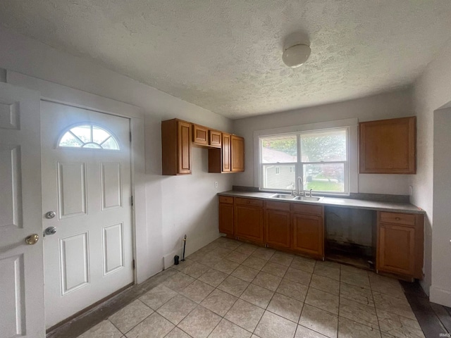 kitchen featuring light tile patterned floors, sink, a wealth of natural light, and a textured ceiling