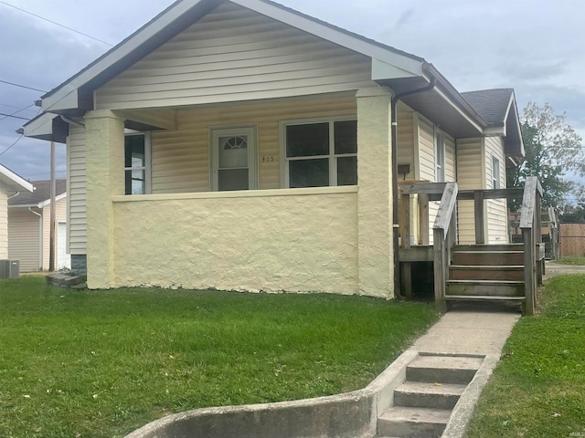 view of front of home featuring a porch, central air condition unit, and a front yard