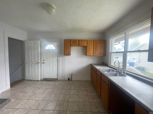 kitchen featuring light tile patterned floors, a textured ceiling, sink, and a healthy amount of sunlight