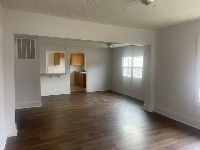 unfurnished living room with dark wood-type flooring and a textured ceiling