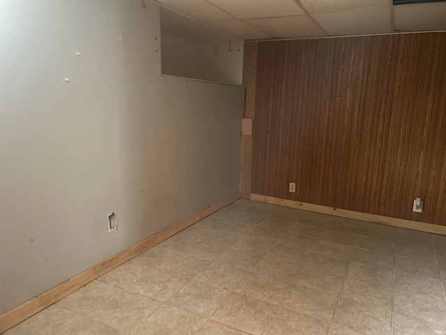 unfurnished room featuring wooden walls and a paneled ceiling