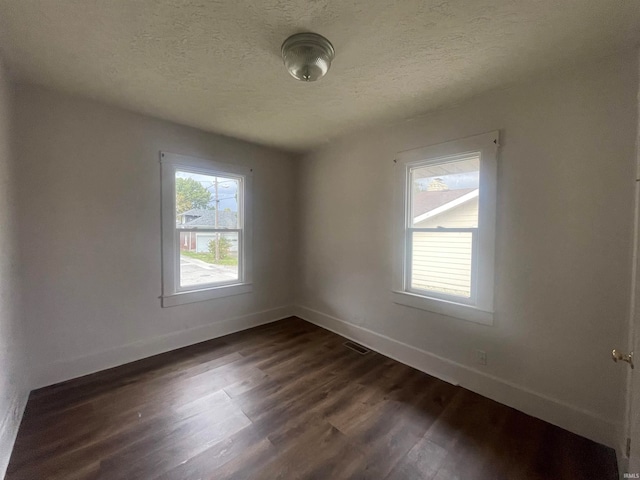 spare room with a textured ceiling and dark hardwood / wood-style flooring