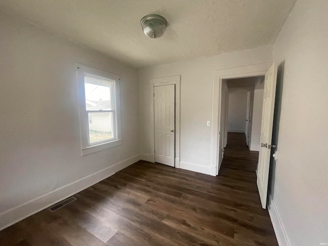 unfurnished bedroom with a closet, dark hardwood / wood-style flooring, and a textured ceiling