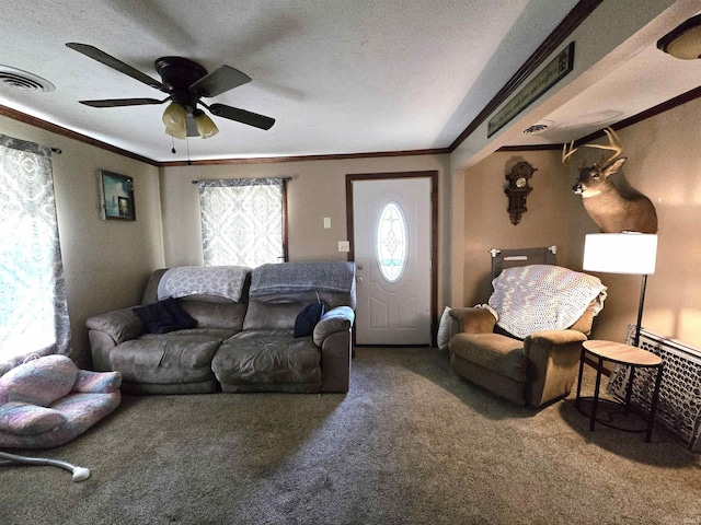 living room with ceiling fan, a textured ceiling, ornamental molding, and carpet