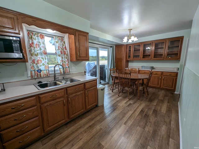 kitchen with a chandelier, pendant lighting, stainless steel microwave, sink, and dark hardwood / wood-style floors