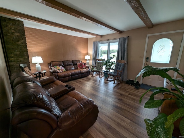 living room with brick wall, dark hardwood / wood-style floors, and beam ceiling