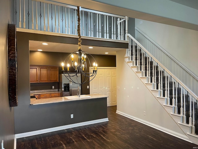 kitchen featuring dark wood-type flooring, sink, a high ceiling, hanging light fixtures, and stainless steel fridge with ice dispenser