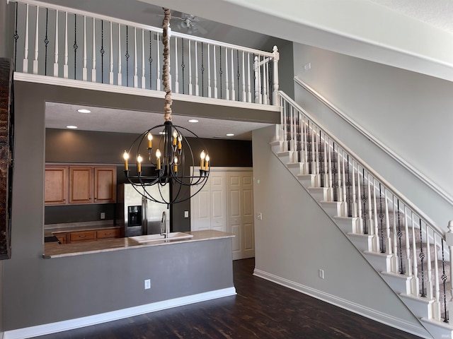 kitchen with sink, dark wood-type flooring, stainless steel fridge with ice dispenser, a chandelier, and a towering ceiling