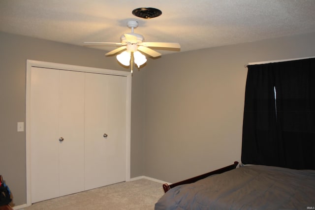 unfurnished bedroom featuring light carpet, ceiling fan, a closet, and a textured ceiling