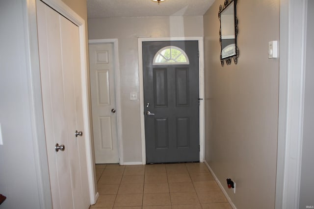 entryway with a textured ceiling and light tile patterned floors