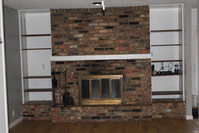 unfurnished living room with a brick fireplace, a textured ceiling, and hardwood / wood-style flooring