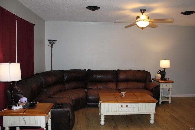 living room with ceiling fan, dark wood-type flooring, and a textured ceiling