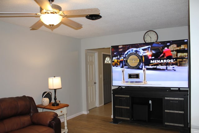 living room featuring ceiling fan, wood-type flooring, and a textured ceiling