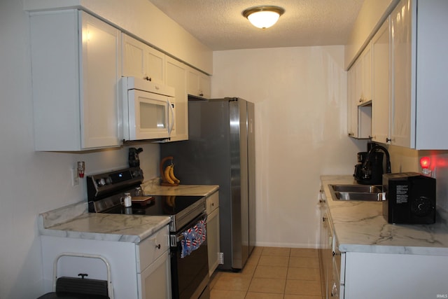 kitchen featuring light tile patterned floors, white cabinets, a textured ceiling, and range with electric stovetop