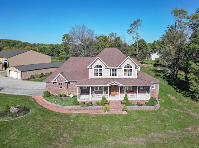 view of front of home featuring an outbuilding, a porch, a front yard, and a garage