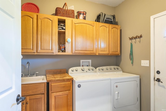 clothes washing area featuring washer and dryer, sink, and cabinets