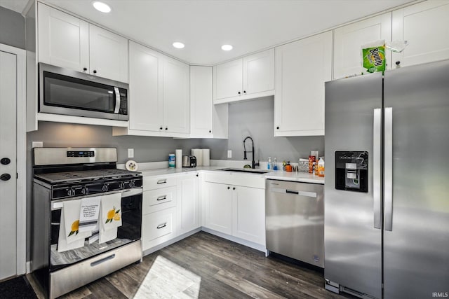 kitchen with white cabinets, sink, stainless steel appliances, and dark hardwood / wood-style flooring