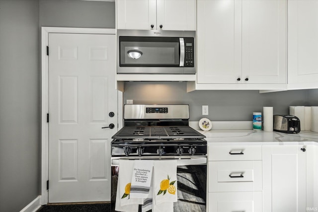 kitchen featuring light stone counters, appliances with stainless steel finishes, and white cabinetry