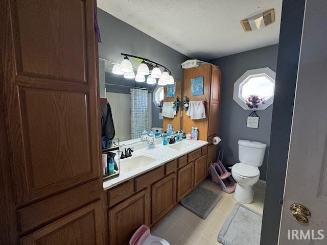 bathroom with vanity, toilet, and a textured ceiling