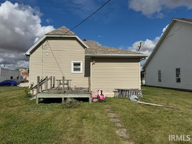 back of property with a deck and a lawn