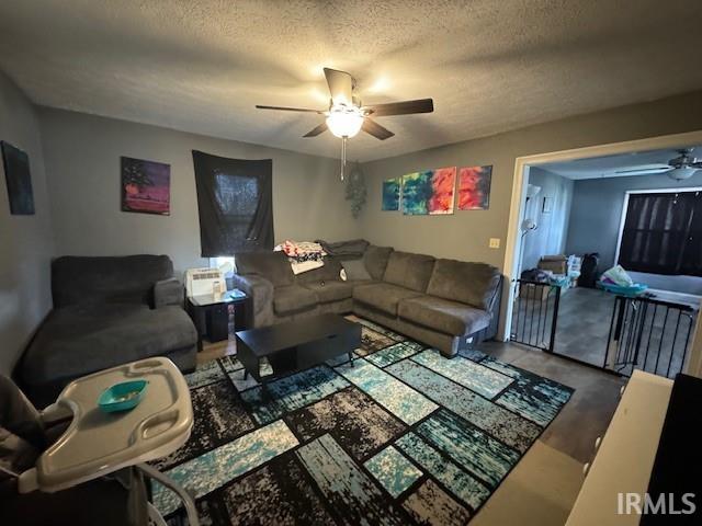 living room with hardwood / wood-style floors, a textured ceiling, and ceiling fan