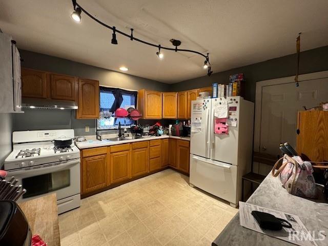 kitchen with white appliances, sink, and rail lighting