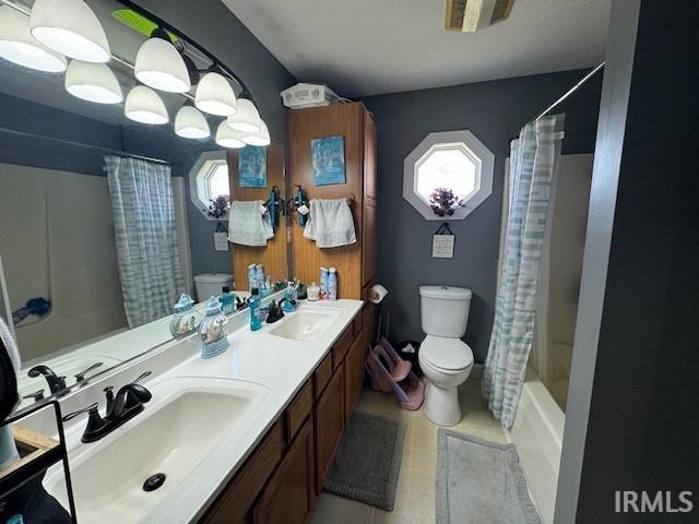 full bathroom with shower / bath combination with curtain, plenty of natural light, vanity, and toilet