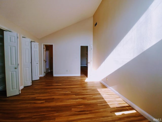 hallway featuring high vaulted ceiling and dark hardwood / wood-style flooring