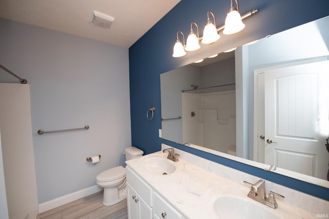 bathroom with a shower, hardwood / wood-style flooring, vanity, and toilet