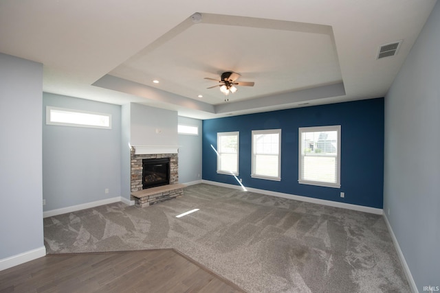 unfurnished living room with wood-type flooring, a tray ceiling, and a wealth of natural light