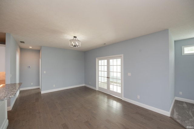 unfurnished living room with a notable chandelier, plenty of natural light, and dark wood-type flooring