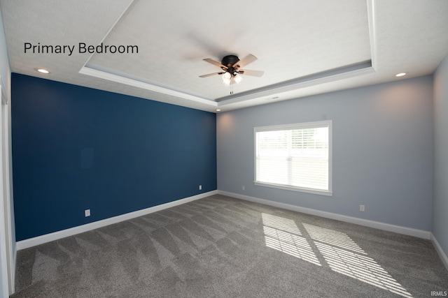 carpeted empty room featuring a tray ceiling and ceiling fan