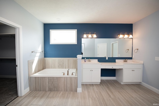 bathroom featuring tiled bath, hardwood / wood-style floors, and vanity