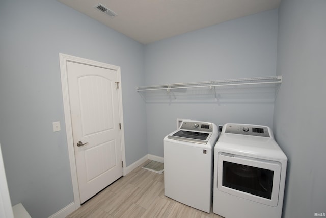 laundry room with washer and clothes dryer and light hardwood / wood-style flooring