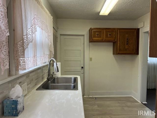 kitchen featuring a textured ceiling, light hardwood / wood-style floors, and sink