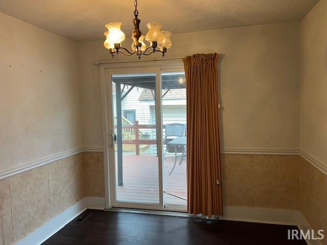 doorway to outside with an inviting chandelier and dark hardwood / wood-style flooring