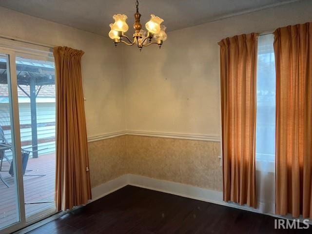 empty room featuring a notable chandelier and dark hardwood / wood-style flooring