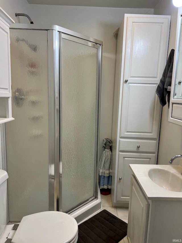 bathroom with vanity, a shower with shower door, toilet, and tile patterned flooring