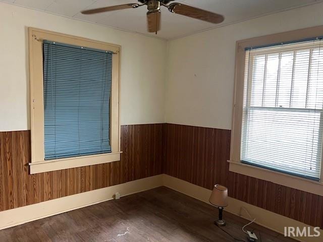 empty room with wood walls, dark hardwood / wood-style flooring, and ceiling fan